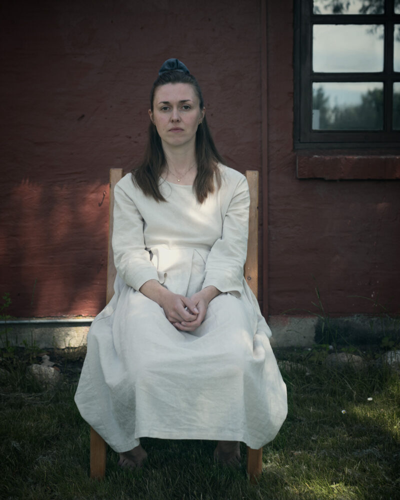 Kvinde på stol foran hus